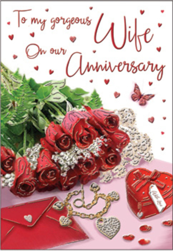 This anniversary card image is styled like an intimate arrangement on a bedside table in Walworth, capturing the essence of enduring love in meticulously chosen details. At the heart of the design lies a posy of crimson roses, tightly gathered and beautifully open, with layered petals that form soft, swirling rosettes. The petals display subtle variations in shade, from vivid red highlights to deeper, almost burgundy shadows at the centre, suggesting rich texture and softness. The roses are framed by sprigs of greenery and delicate foliage, adding contrast and a sense of freshness, as though they were just arranged by hand at a local floristry bench. To one side of the bouquet rests a small, plush-looking jewellery box in a saturated red tone, its shape compact and its surface satin-smooth, topped with a simple ribbon detail. A fine golden necklace, crafted into twin heart shapes, lies gently across the card's surface, its chain forming relaxed curves that reflect the warm light. Around these central elements, a sprinkling of tiny heart-shaped decorations and subtle sparkling accents gives the impression of a celebratory scattering, like confetti after a special toast. Flowing calligraphic text runs across the card, partially encircling the roses and jewellery, its script refined and romantic, even if the exact words are not fully legible. The light falls softly over the entire composition, emphasising the lustre of the metal and the luxurious depth of the roses' petals. The atmosphere is one of quiet celebration and shared promises, echoing the kind of heartfelt anniversary moment a Walworth couple might create at home after a relaxed dinner and a slow stroll past the familiar streets surrounding Elephant and Castle.