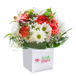 Channeling the playful vibrancy of Walworth, this bouquet feels like a fresh burst of spring delivered right to your doorstep. Nestled in a pure white square gift bag, the arrangement blends plush, coral-hued carnations-each with ruffled, velvety petals and gentle gradients of pink and peach-with crisp white daisies highlighted by lively lime-yellow centres. Wisps of baby's breath wind their way through the bouquet, lending an airy lightness and delicate movement, almost as if capturing the gentle flow of a breeze along East Street. A few purple-tipped buds, still closed, nestle quietly among the open blooms, hinting at joy yet to unfold. Glossy, deep green leaves cradle the flowers, anchoring the design with a touch of classic greenery reminiscent of Walworth's lush public gardens. The white ribbon handles of the bag suggest a convenient gift, perfect for delivering a smile or a congratulatory message whether you're near the Elephant and Castle or by Walworth Garden Farm. Every stem and petal is carefully positioned, highlighting the hand-crafted expertise and joyful intent that make this bouquet ideal for birthdays, anniversaries, or simply celebrating the local spirit of Walworth with a floral surprise.